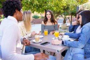 grupo multiétnico de amigos tomando uma bebida juntos em um bar ao ar livre. foto