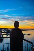 tiro panorâmico de uma silhueta por trás olhando para o lago e o lindo pôr do sol foto