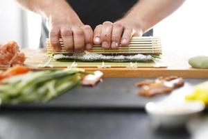mestre de sushi prepara futomaki foto