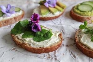sanduíches de rosto aberto de fermento verde com flores comestíveis roxas