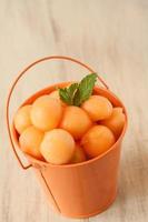bolas de melão no balde laranja foto