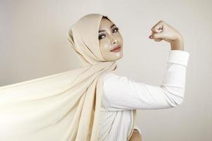 linda jovem muçulmana forte isolada sobre a parede de fundo branco mostrando o bíceps. foto