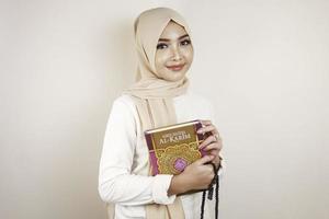 jovem mulher muçulmana asiática sorrindo e segurando o Alcorão foto
