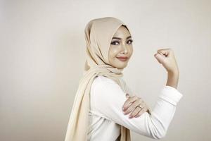 linda jovem muçulmana forte isolada sobre a parede de fundo branco mostrando o bíceps. foto