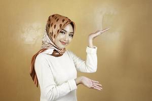 alegre jovem muçulmana asiática apontando o lado para copiar o espaço com sorriso foto