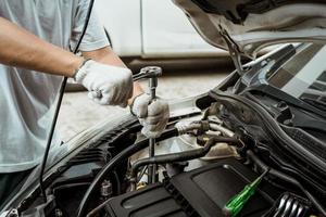 mecânico usando uma chave e soquete e reparando o motor do carro na garagem, conceito de carro de reparo de manutenção, foco seletivo foto