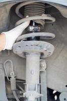 mecânico inspeciona carro na garagem com amortecedores antigos. conceito foto