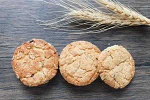 três deliciosos biscoitos de aveia com espigas na mesa de madeira. foto