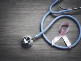 fita rosa de conscientização de câncer de mama com estetoscópio médico em fundo de madeira, símbolo de outubro, conceito de saúde e medicina foto