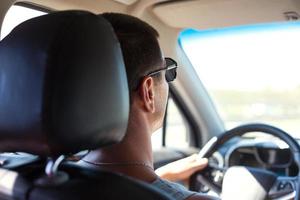 um homem de óculos escuros está dirigindo um carro. segurança rodoviária, regras de trânsito, viagens de automóvel, navegador foto