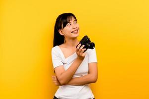 garota fotógrafa tirando fotos. modelo isolado em fundo amarelo. com espaço de cópia foto