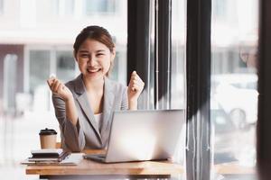 mulher de negócios asiática atraente feliz trabalhando com um laptop e documento financeiro no escritório, ação bem sucedida, conceito de negócio. foto