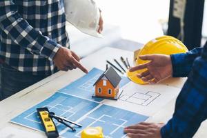 arquitetos conceituais, engenheiro segurando caneta apontando arquitetos de equipamentos na mesa com uma planta no escritório, engenheiros e arquitetos trabalham em projetos de brainstorming. foto