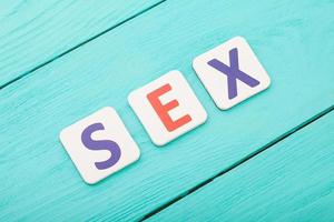 palavra de sexo por blocos de letra sobre fundo azul de madeira. vista do topo. copie o espaço. foto
