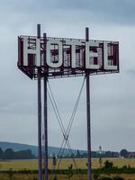 tiro vertical de um sinal de hotel em um poste contra um céu azul nublado durante o dia foto