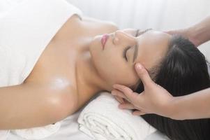 jovem mulher bonita asiática relaxando e desfrutando de massagem na cabeça, spa e conceito de tratamento de beleza foto