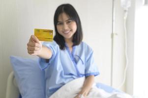 uma jovem paciente está segurando cartão de crédito, admitindo no hospital, conceito de cuidados de saúde foto