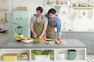 jovem casal gay sorridente cozinhando juntos na cozinha em casa, lgbtq e conceito de diversidade. foto