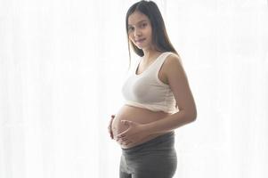 jovem e bela mulher grávida em casa, conceito de cuidados de maternidade e gravidez foto