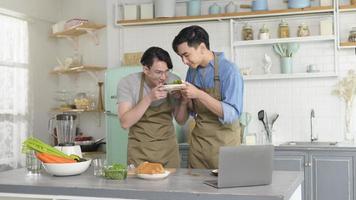 jovem casal gay sorridente cozinhando juntos na cozinha em casa, lgbtq e conceito de diversidade. foto