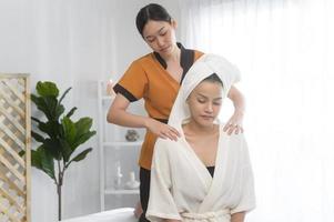 jovem mulher bonita asiática relaxando e desfrutando do conceito de massagem, spa e tratamento de beleza foto