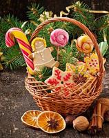 biscoitos de gengibre de natal e pirulitos em uma cesta em fundo de madeira velho foto