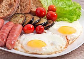 café da manhã inglês - ovos fritos, salsichas, berinjela e tomate foto