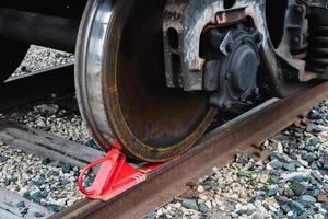 sapato vermelho de freio ferroviário sob a roda de um trem sobre trilhos. foto