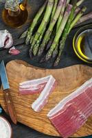 preparação de prato simples italiano, aspargos e bacon foto