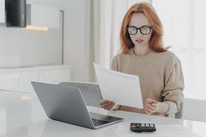 economista feminina profissional calcula finanças em casa mantém documento em papel faz relatório financeiro foto