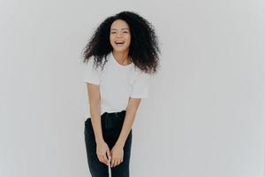 foto de estúdio de alegre mulher afro-americana ri alegremente, vestida com roupas casuais, se sente bem, posa contra um fundo branco com espaço em branco para o seu conteúdo publicitário, sente-se energizado