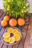 prato com laranjas e vasos de plantas em uma mesa de madeira foto