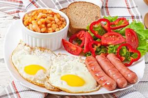 café da manhã inglês - salsichas, ovos, feijão e salada foto
