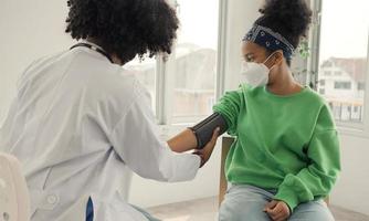 médico americano africano está medindo a pressão arterial e verificando o pulso do paciente infantil. foto
