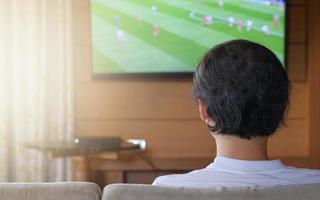 vista traseira do homem asiático jogando futebol no console de férias em casa, efeito de luz. foto