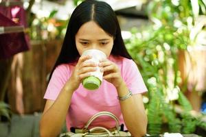 mulher asiática bebendo chá verde em um café