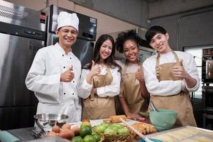 retrato de pessoas de classe profissional de culinária, chef masculino sênior e equipe de jovens estudantes olhando para a câmera, sorriso alegre e polegar para cima na cozinha, alimentos de pastelaria e curso de padaria para pequenas empresas. foto