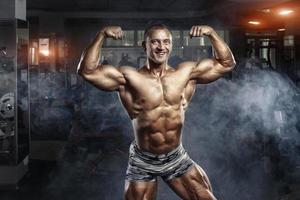 homem fisiculturista posando no ginásio foto