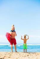 pai e filhos indo surfar