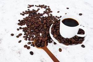 xícara de café e grãos de café em fundo branco.