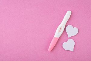 teste de gravidez positivo com corações isolados no fundo rosa foto