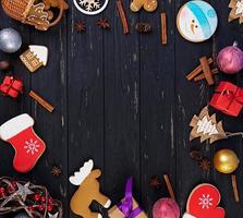 fundo de natal. presente de natal, brinquedos, biscoitos de gengibre, especiarias e decorações em fundo de madeira. vista do topo foto