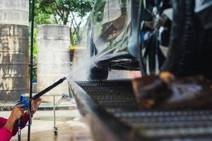 mão segurando a pistola de pulverização de água de alta pressão, limpando carros na loja de lavagem de carros foto