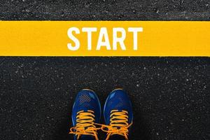 palavra começa na linha amarela com tênis azul ou sapatos esportivos no fundo da estrada de asfalto. foto