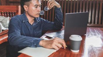 homem de negócios teleconferência do homem de negócios em casa em reunião usando seu computador portátil e escrevendo notas foto