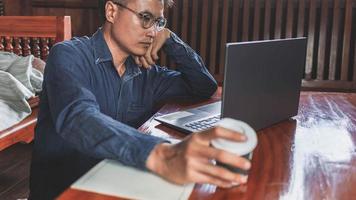 homem de negócios teleconferência do homem de negócios em casa em reunião usando seu computador portátil e escrevendo notas foto