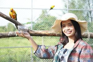 mulher asiática sorrindo alegremente alimenta o papagaio foto