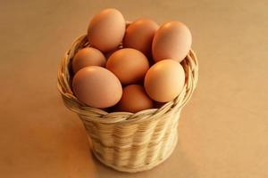 uma cesta de ovos de galinha em uma mesa de madeira foto