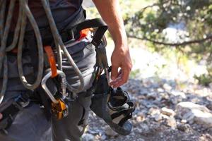 equipamento de escalada em sapatos de rocha alpinista masculino, corda, quickdraw, dispositivo de segurança, arnês. turismo esportivo de montanha, estilo de vida ativo, esportes radicais foto