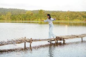 turista asiática caminha na ponte de bambu para chegar ao ponto de vista foto